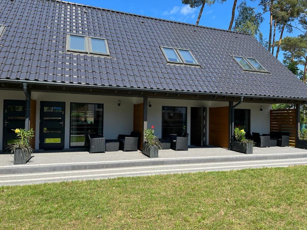 a building with chairs and plants in front of it at Nowe Domki Letniskowe in Pobierowo
