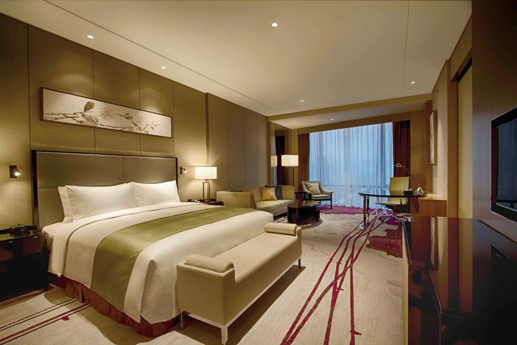 a bedroom with a large bed and a living room at DoubleTree by Hilton Heyuan in Heyuan