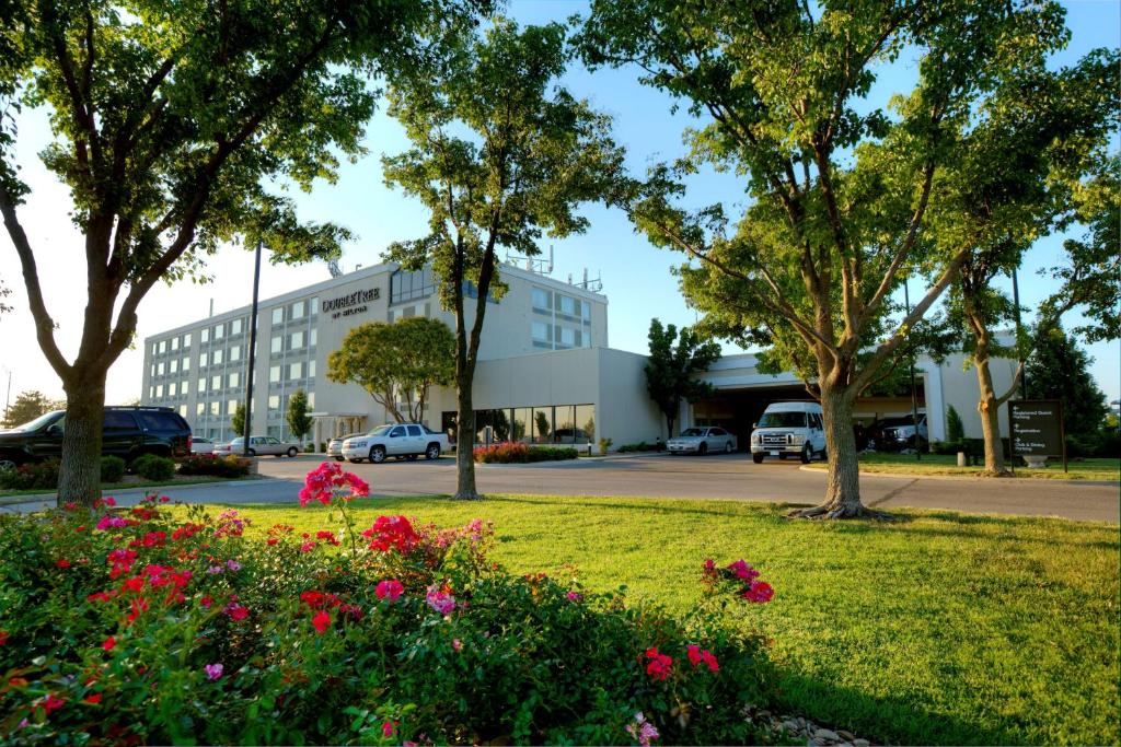 a park with flowers in front of a building at DoubleTree by Hilton Wichita Airport in Wichita