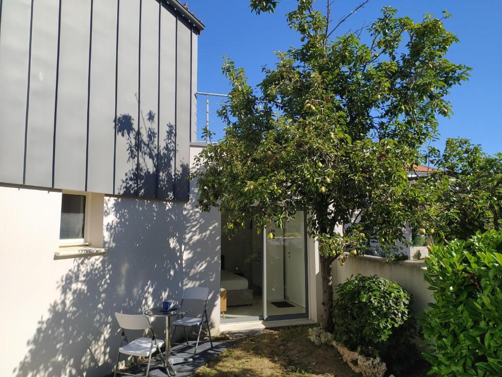une extension en verre d'une maison avec un arbre dans l'établissement Belle Maisonnette avec jardin 2 pas du VIEUX PORT, à La Rochelle