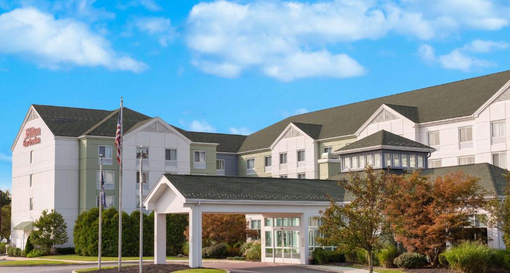 a large white building with a flag in front of it at Hilton Garden Inn Islip/MacArthur Airport in Ronkonkoma