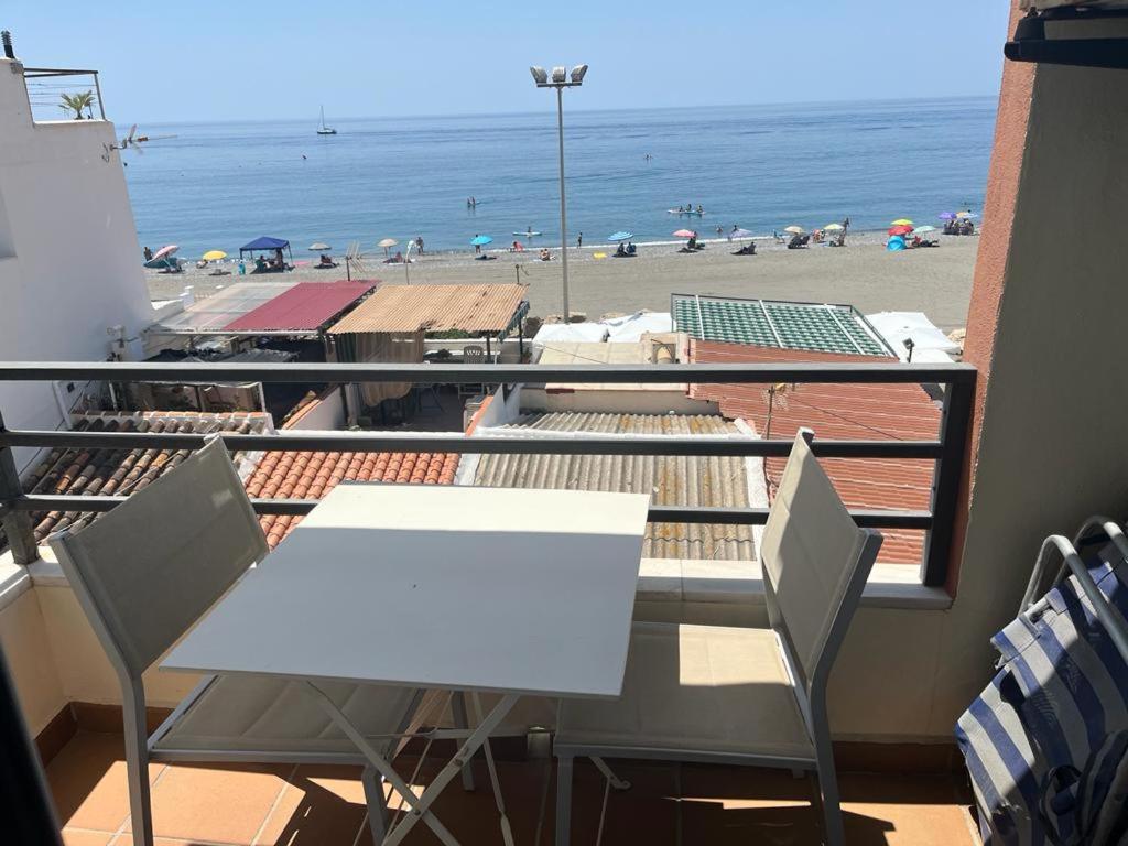einen weißen Tisch und Stühle auf einem Balkon mit Strand in der Unterkunft Maravilloso apartamento en primera linea de playa con vistas al mar en Caleta de Vélez 2 C in Caleta De Velez
