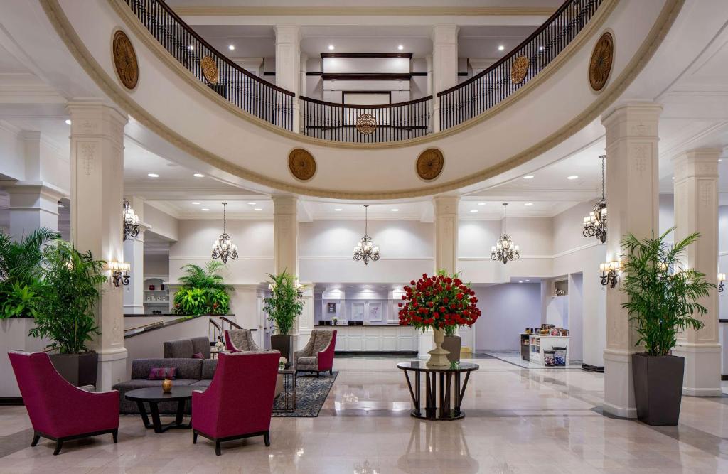 a lobby with a large staircase with red chairs at Hilton Garden Inn Jackson Downtown in Jackson