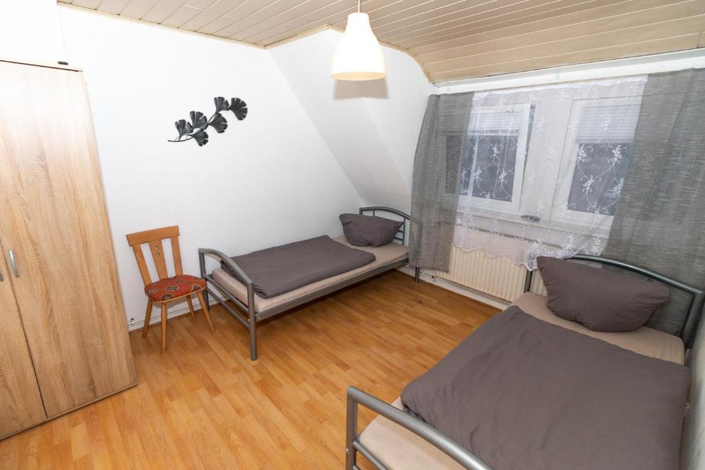 Cette chambre comprend un lit, une chaise et une fenêtre. dans l'établissement Wohnung nähe Daimler 1 OG, à Brême