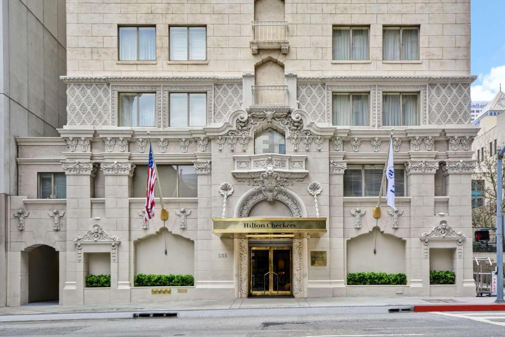 a building on the corner of a street with flags at Hilton Checkers Los Angeles in Los Angeles