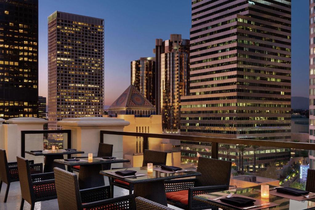 a restaurant with tables and chairs and a city skyline at Hilton Checkers Los Angeles in Los Angeles