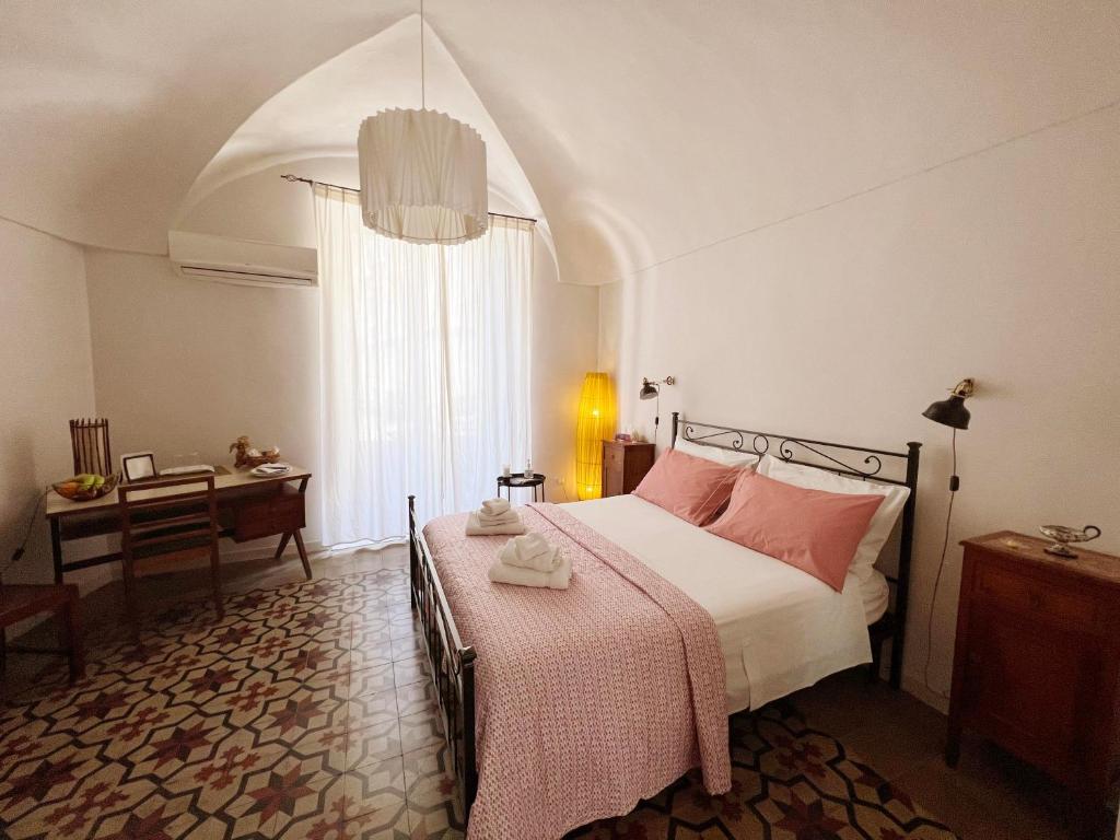 Schlafzimmer mit einem Bett mit rosa Kissen und einem Tisch in der Unterkunft Jasper B&B in Catania