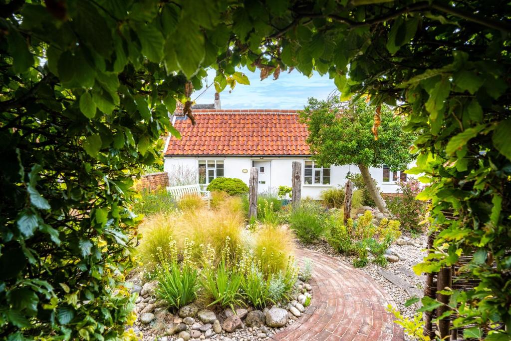 Myrtle Cottage في Friston: منزل مع حديقة من خلال الممر