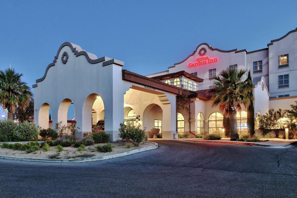 a hotel with palm trees in front of a building at Hilton Garden Inn Las Cruces in Las Cruces