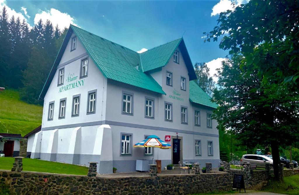ein großes weißes Gebäude mit grünem Dach in der Unterkunft HAMR Apartmány in Nové Hamry