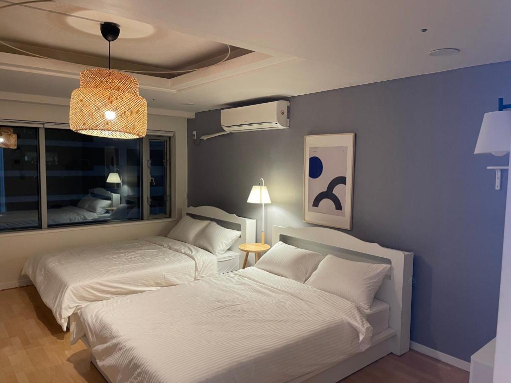a bedroom with two beds and a blue wall at WinSome_HongDae in Seoul