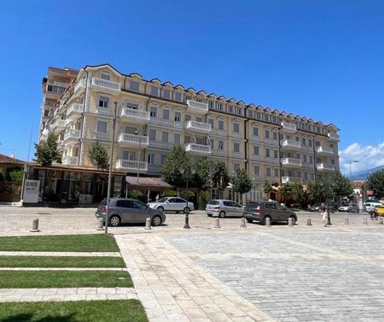 un gran edificio con coches estacionados en un estacionamiento en Appartamento Hakuna Matata, en Shkodër
