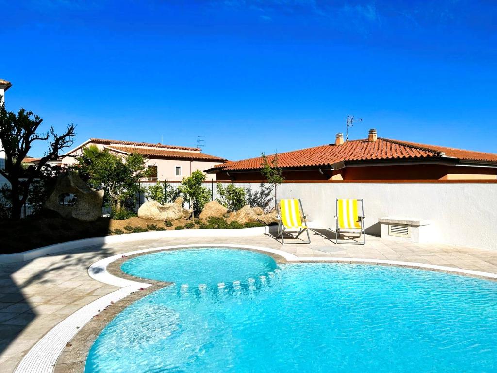 una piscina con 2 sillas y una casa en Villa Ada Olbia en Olbia