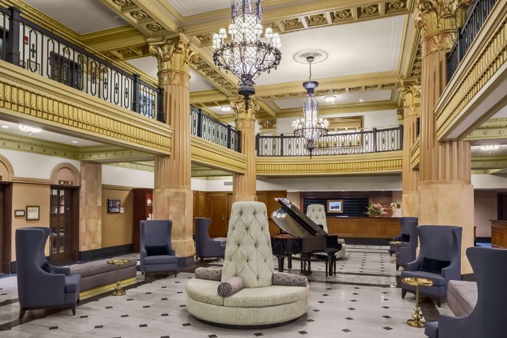 a large lobby with a piano and a chair at Hilton President Kansas City in Kansas City