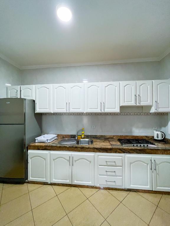 a kitchen with white cabinets and a stainless steel refrigerator at Rif Appartment in Al Hoceïma