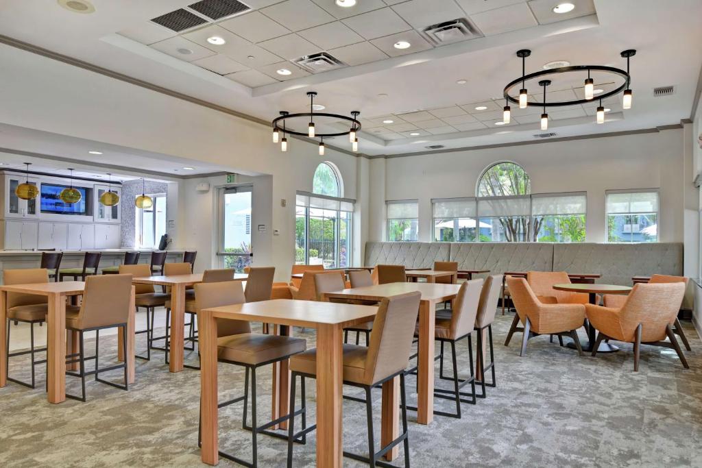 a dining room with tables and chairs and windows at Hilton Garden Inn Orlando Lake Buena Vista in Orlando