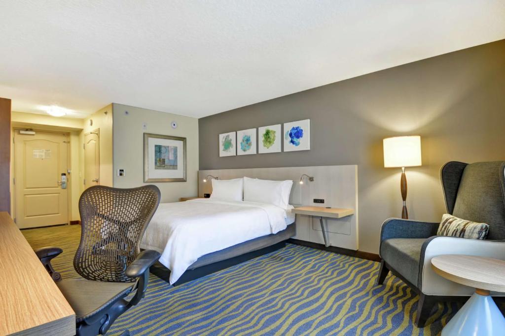 a hotel room with a bed and a desk and a chair at Hilton Garden Inn Orlando Lake Buena Vista in Orlando