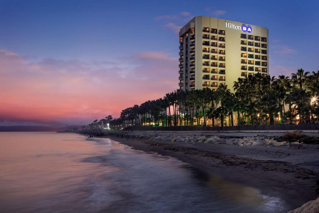 a hotel on the beach at dusk with the ocean at Mersin HiltonSA in Mersin