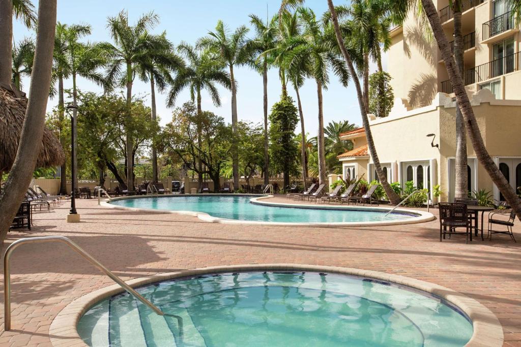 una piscina en un complejo con palmeras en Embassy Suites by Hilton Miami International Airport en Miami