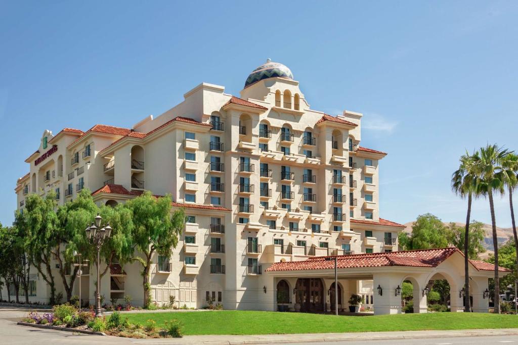 a large building with palm trees in front of it at Embassy Suites by Hilton Milpitas Silicon Valley in Milpitas