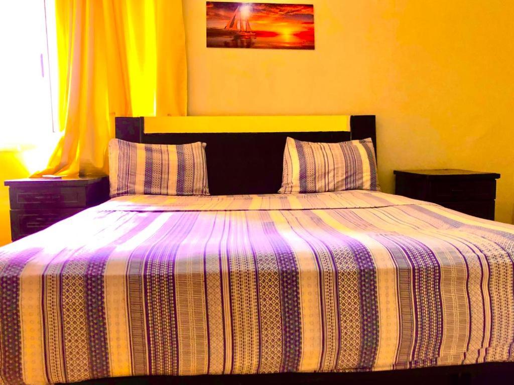 a bed with a striped comforter in a bedroom at Hôtel Ami Bamba in Mbour