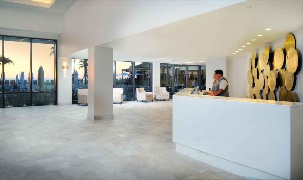 a man standing at a counter in a lobby with a view at Hilton Marco Island Beach Resort and Spa in Marco Island