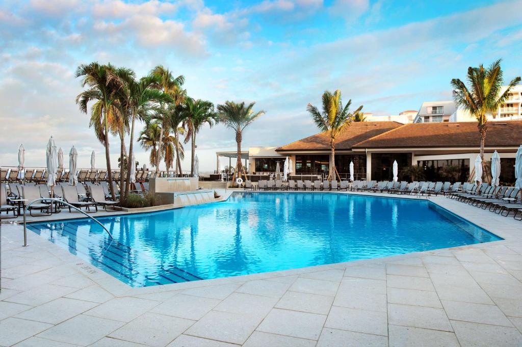 a swimming pool with chairs and palm trees at Hilton Marco Island Beach Resort and Spa in Marco Island