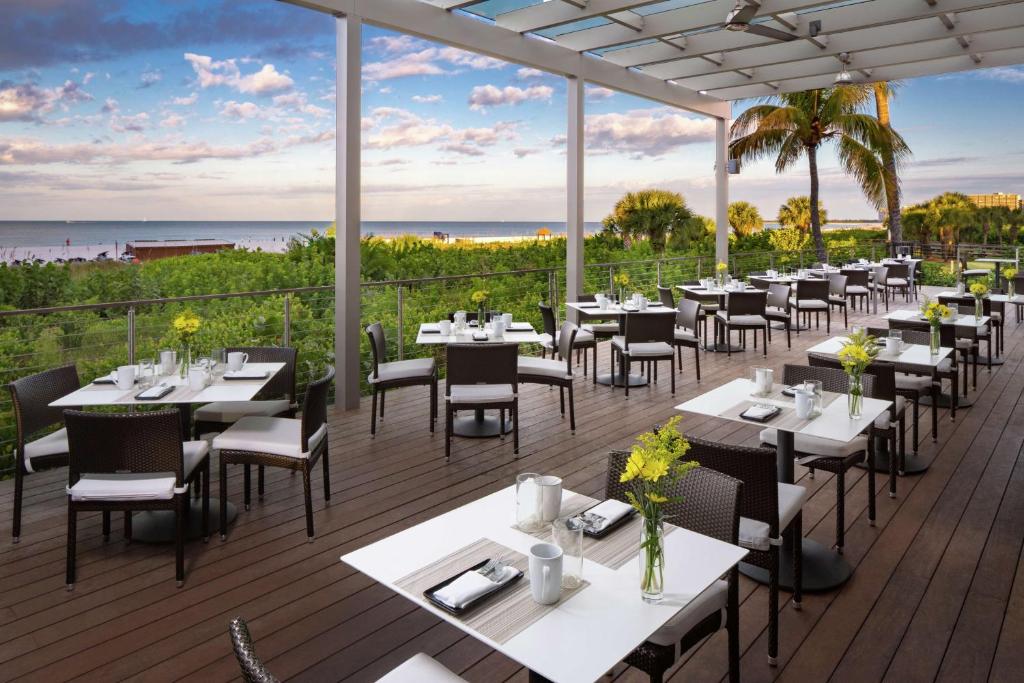 a restaurant with tables and chairs on a deck at Hilton Marco Island Beach Resort and Spa in Marco Island