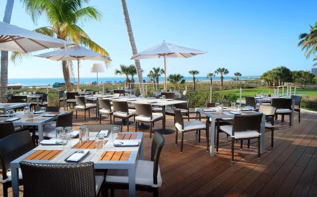 a restaurant with tables and chairs with the ocean in the background at Hilton Marco Island Beach Resort and Spa in Marco Island