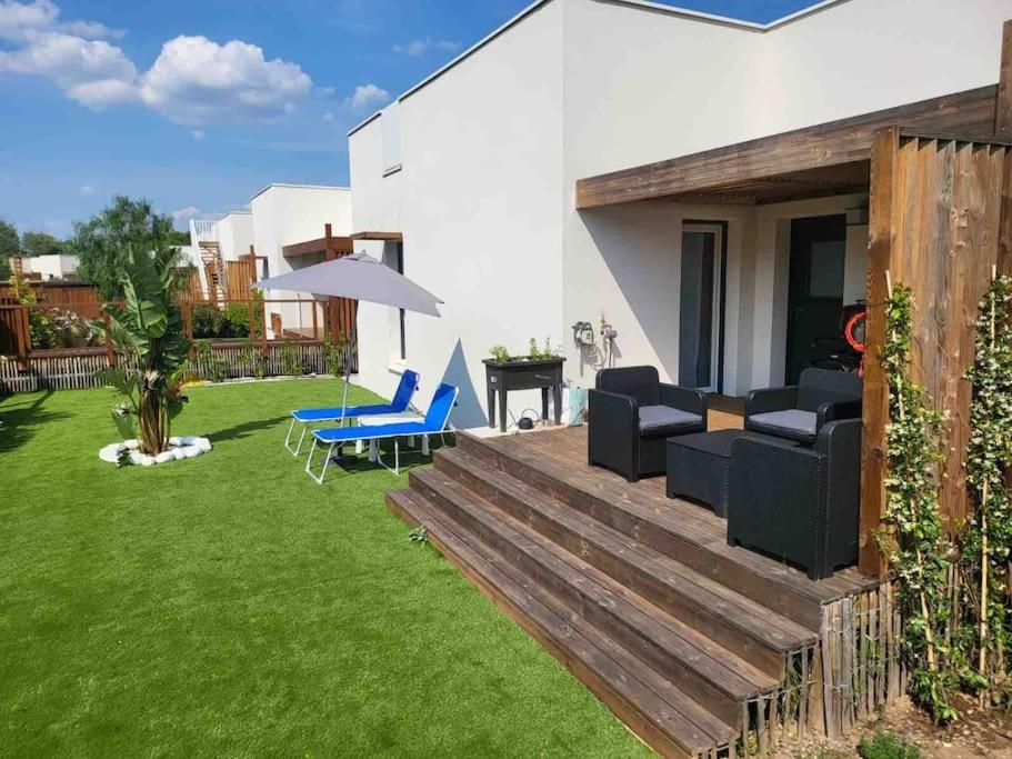 une arrière-cour avec une terrasse munie de chaises et d'un parasol dans l'établissement VILLA VACANCES, à Vias