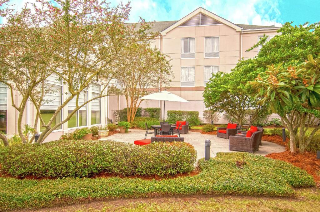 a building with a patio with furniture and trees at Hilton Garden Inn New Orleans Airport in Kenner