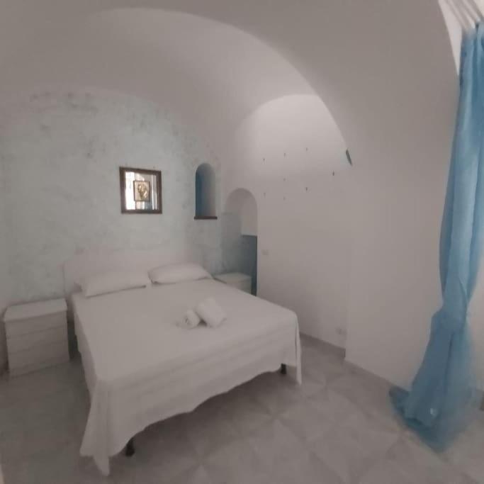 een witte slaapkamer met een wit bed en blauwe accenten bij Casa della Nonna in Atrani