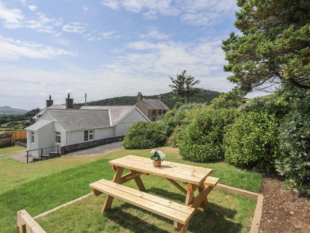 a wooden picnic table in the yard of a house at Glan Awel in Pwllheli