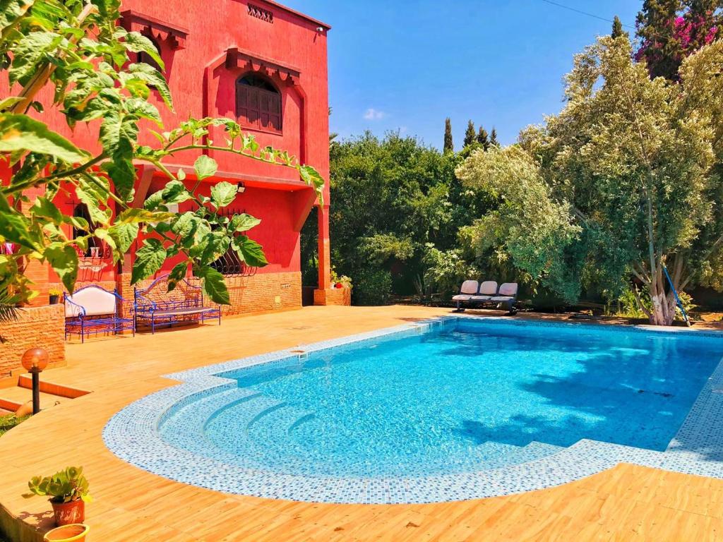 einem Pool vor einem roten Gebäude in der Unterkunft Villa mogador in Essaouira