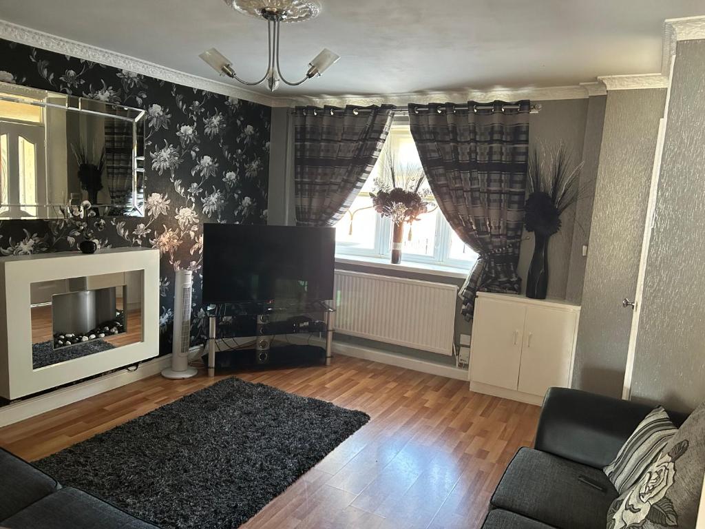 een woonkamer met een bank en een televisie bij 2 bedroom house close to city centre with gated driveway in Liverpool