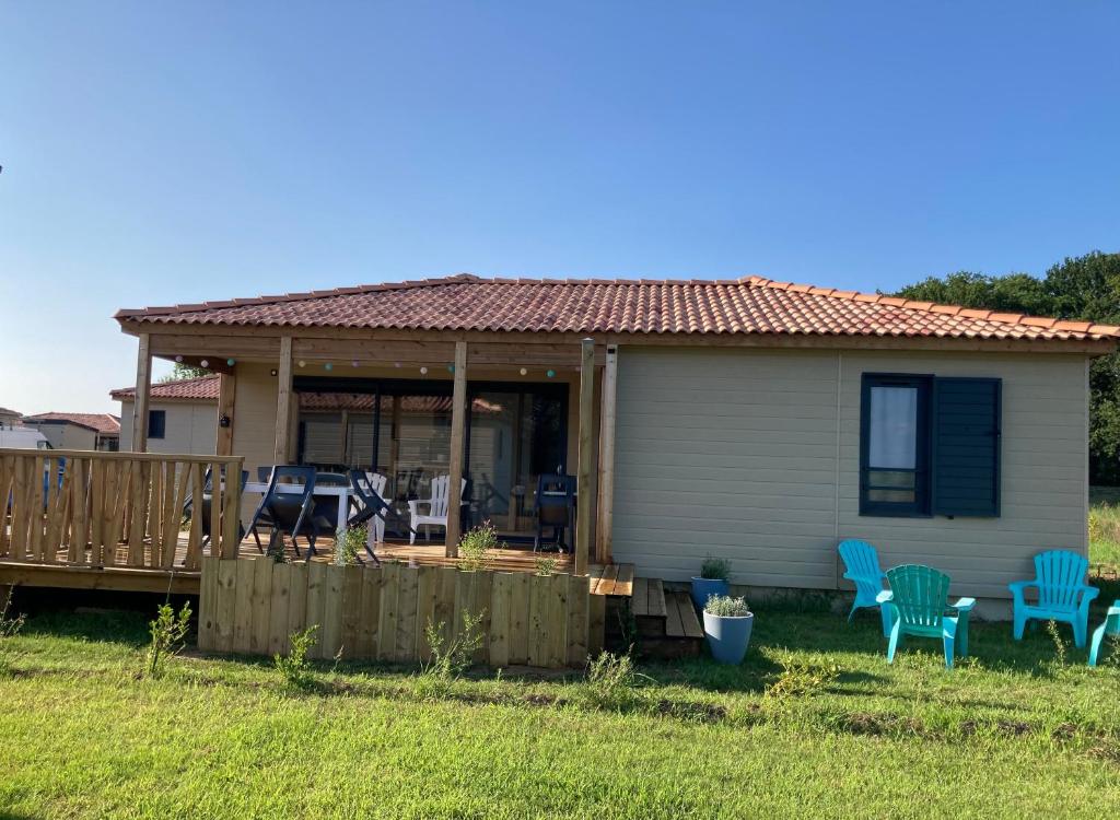 Casa pequeña con porche y sillas azules en Cottage Le Colibri au calme piscine chauffée spa sauna hammam parc multisports en Saubrigues