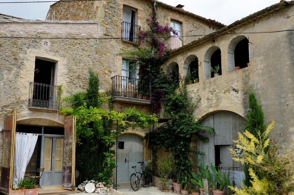 Sant Jordi Desvalls的住宿－CAN TAT, Loft in a old coach house，一座古老的石头房子,前面有一辆自行车停放