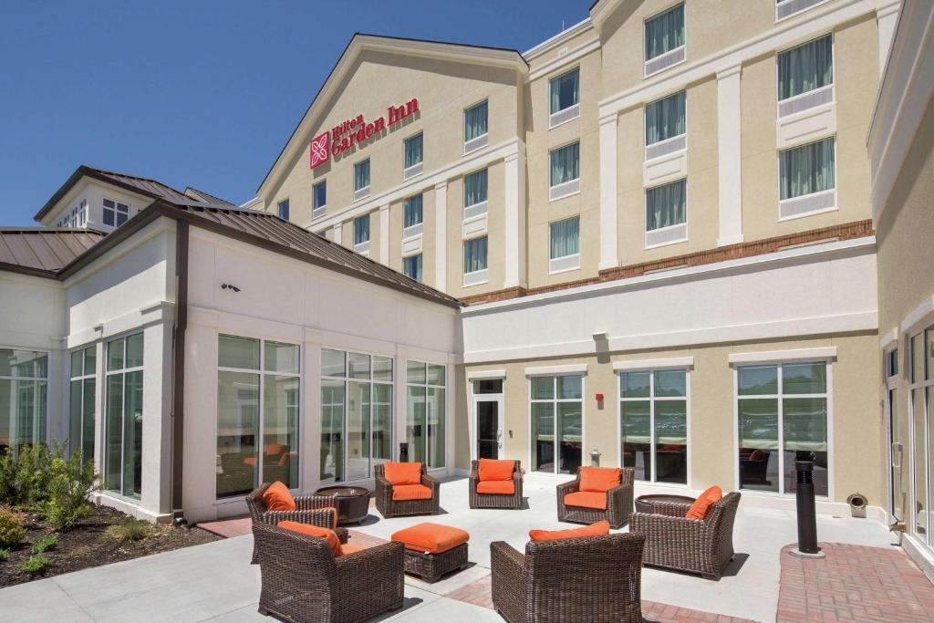 a hotel with chairs and tables in the courtyard at Hilton Garden Inn Pascagoula in Pascagoula