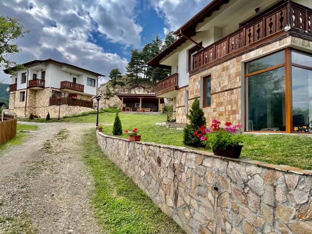 a stone retaining wall in front of a house at Farmhopping Village in Dobărsko