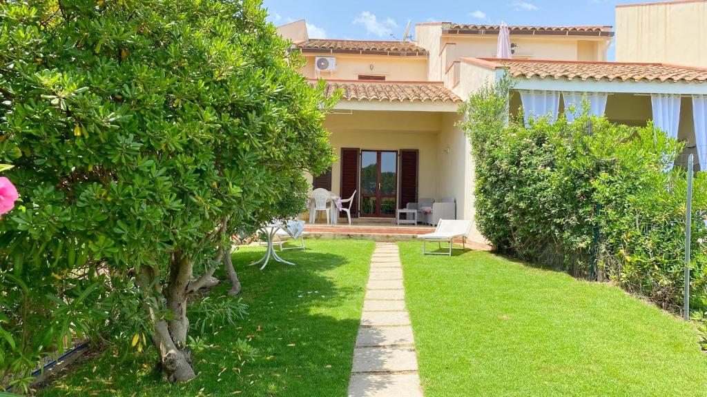 una casa con un cortile con erba verde e alberi di Villetta Turagri 22 a soli 300 m dalla spiaggia 10 posti letto a Costa Rei
