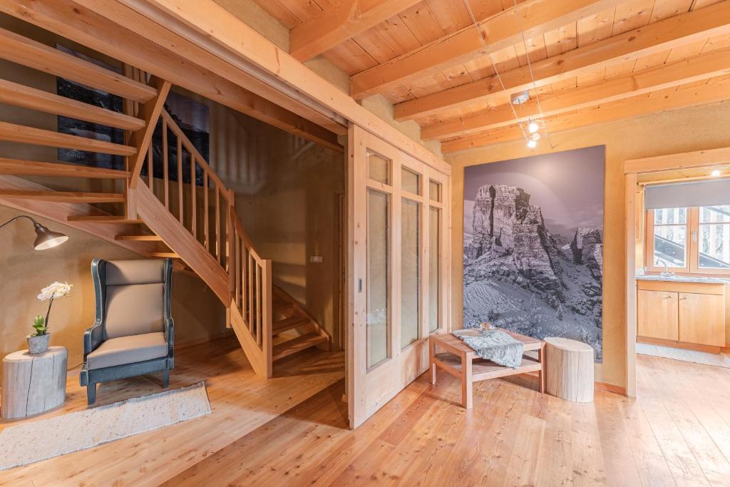 a living room with a staircase and a chair at Eco Chalet Olival in Braies