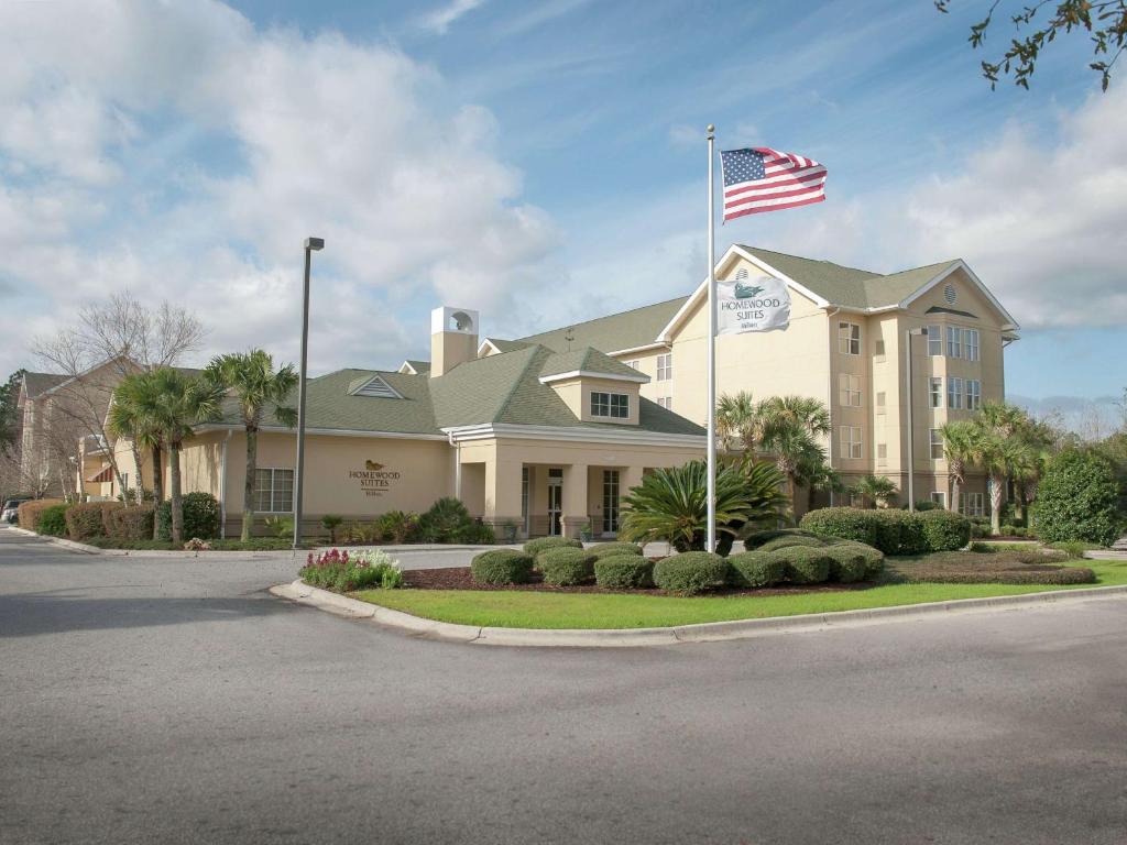 dom z amerykańską flagą przed nim w obiekcie Homewood Suites by Hilton Pensacola Airport-Cordova Mall Area w mieście Pensacola