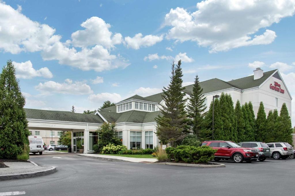 a large white building with cars parked in a parking lot at Hilton Garden Inn Portland Airport in Portland