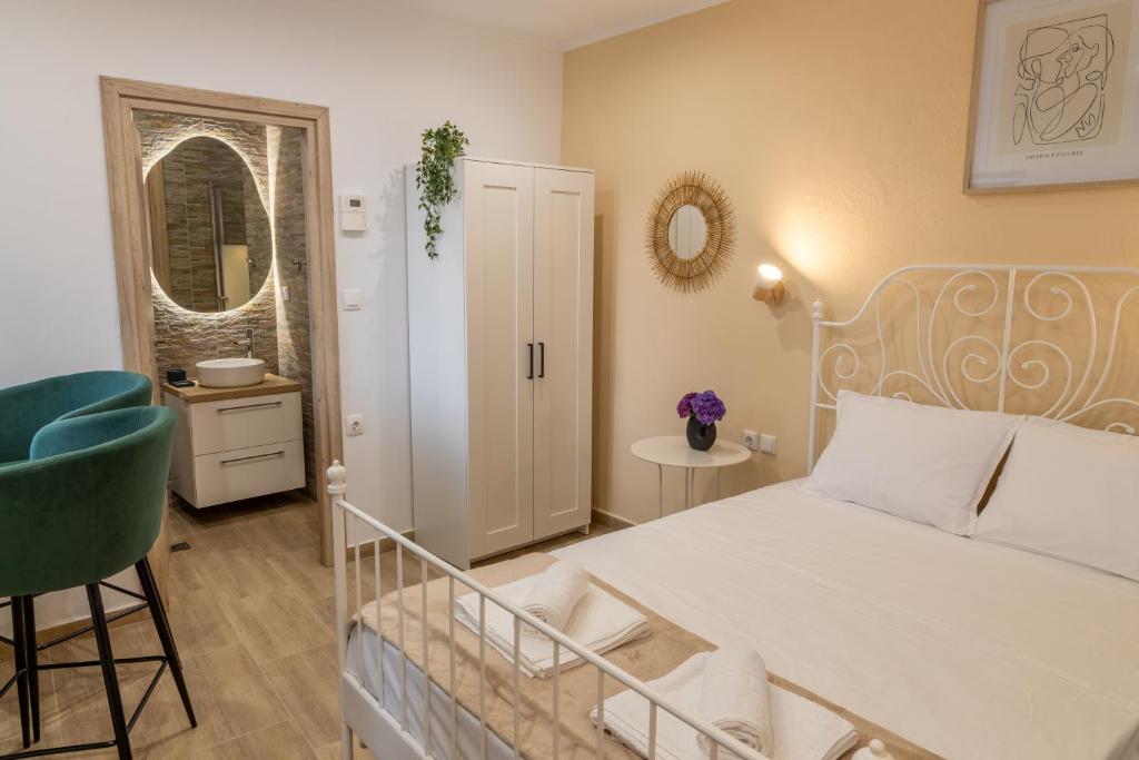 ein Schlafzimmer mit einem weißen Bett und einem grünen Stuhl in der Unterkunft Bardis Hidden Gem in Volos