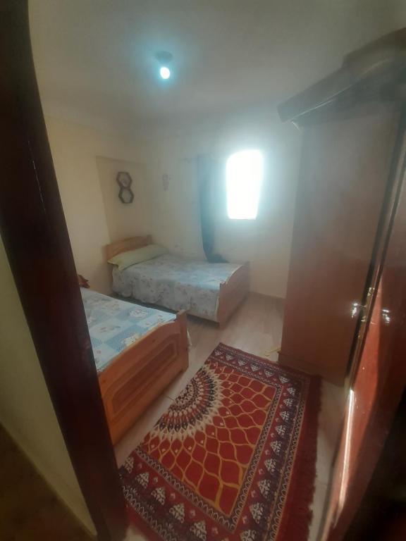 Habitación pequeña con 2 camas y alfombra. en شقة مميزة فى الاسكندرية قرية الزهراء Alexandria, en Alejandría