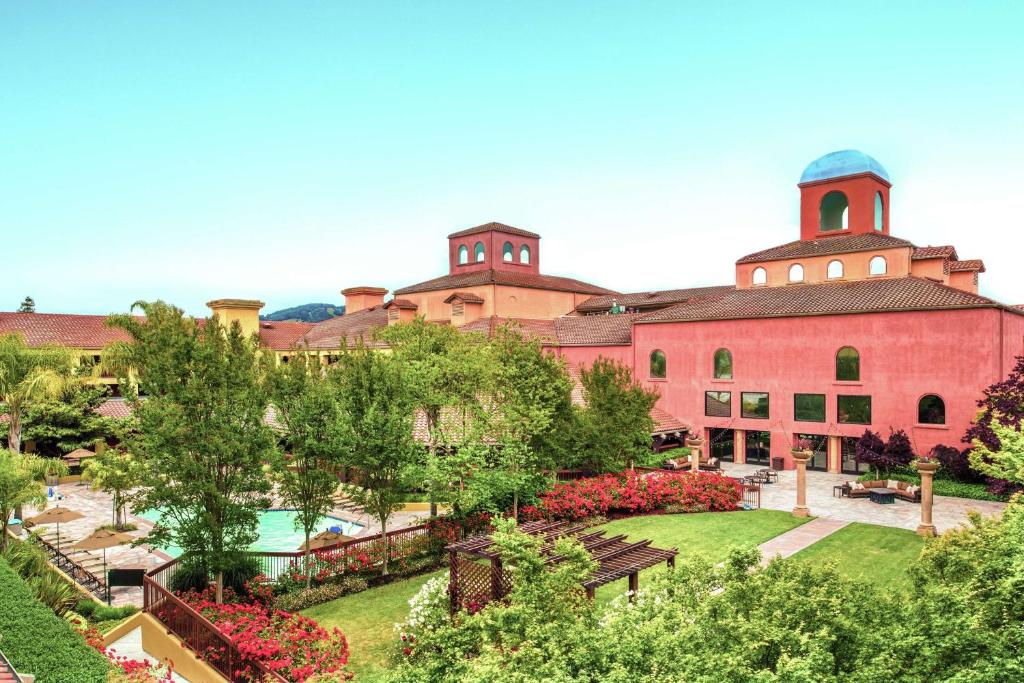un grand bâtiment rouge avec un jardin en face dans l'établissement DoubleTree by Hilton Sonoma Wine Country, à Rohnert Park