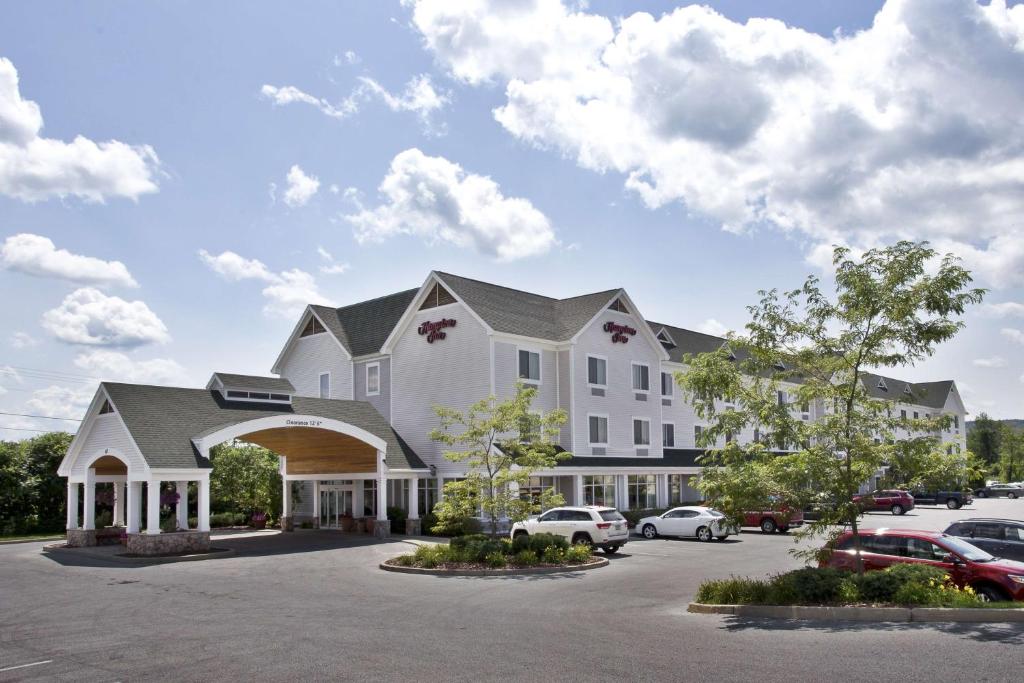 um grande edifício branco com carros estacionados num parque de estacionamento em Hampton Inn Rutland/Killington em Rutland