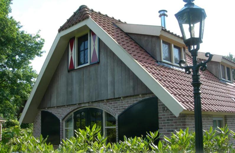 een huis met een gambrel dak en een straatlicht bij Mooie 6 persoons vakantieboerderij in de Achterhoek in Eibergen