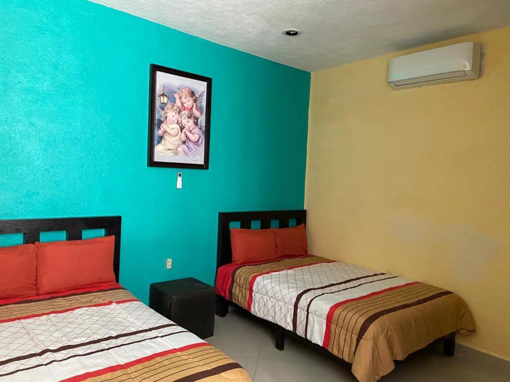 a room with two beds and a blue wall at CONDOMINIO PALMEIRAS in Acapulco