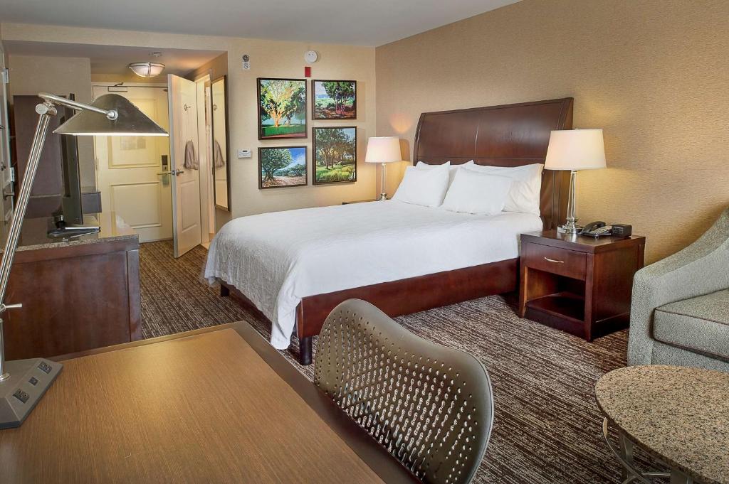 Habitación de hotel con cama y sala de estar. en Hilton Garden Inn St. Louis Airport, en Berkeley